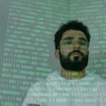 A bearded man in glasses stands with binary code projection, representing cybersecurity and digital intelligence.